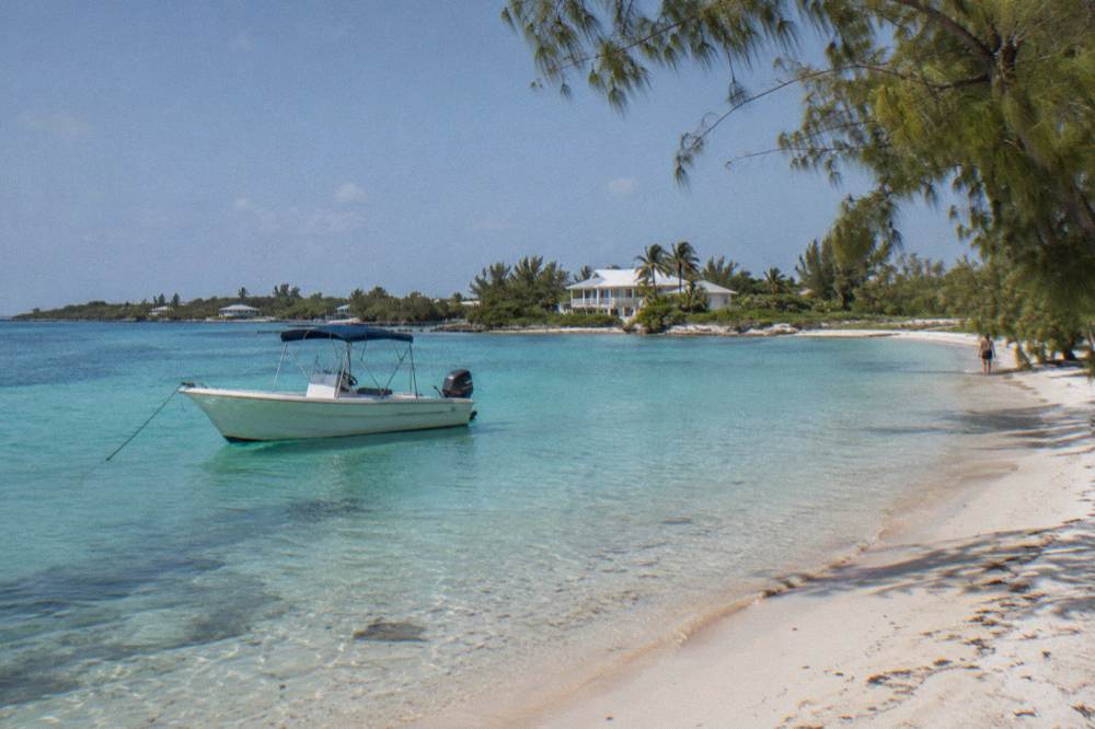 A tour boat anchored in shallow turquoise water near a small beach